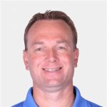 A headshot of a smiling man in a blue polo shirt.
