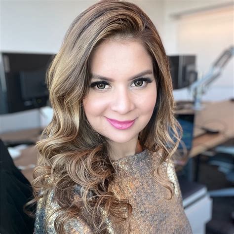 A woman with shoulder-length highlighted hair and pink lipstick smiling at the camera.